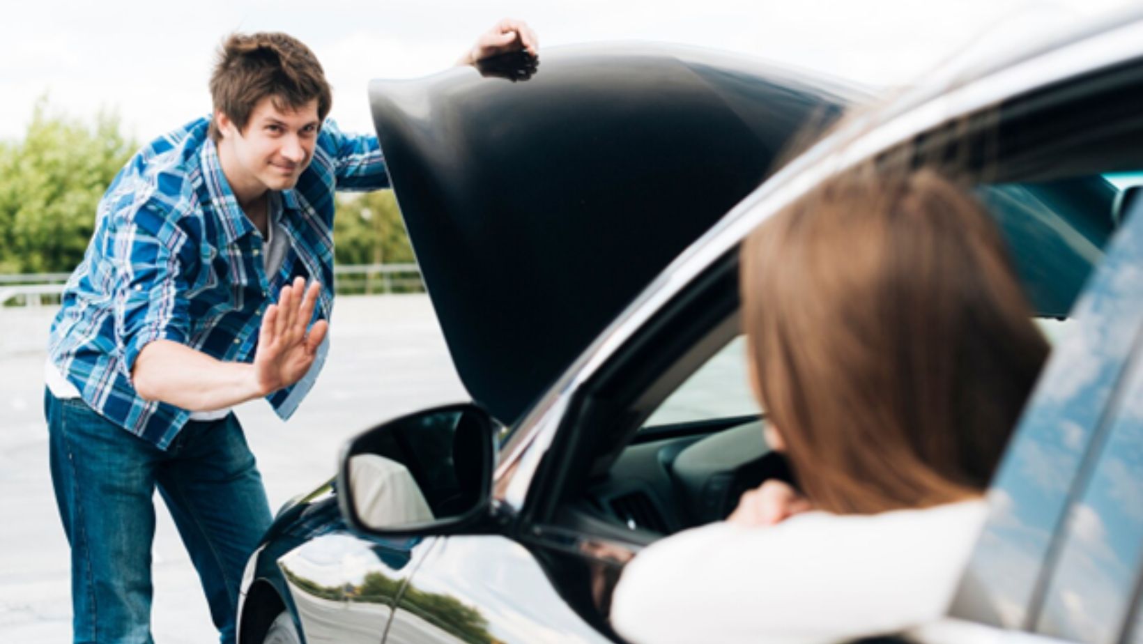 A man checking under the hood of a car while talking to a woman in the driver’s seat.